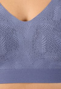 Bralette de encaje morado con un diseño de escote en V, que presenta un patrón de hojas texturizado y una banda inferior suave y elástica.