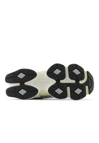 Μαύρη εξωτερική σόλα από καο υτσούκ με σχέδια σε σχήμα διαμαντιού· ενδιάμεση σόλα σε κρεμ χρώμα· λογότυπο "new balance" ανάγλυφο στη φτέρνα· υφή με ανάγλυφη επιφάνεια.