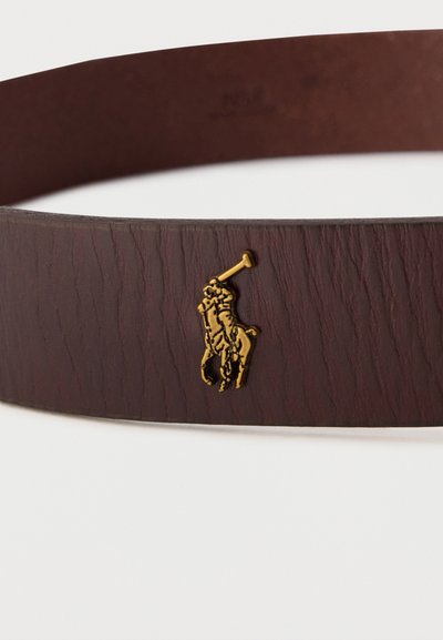 Cintura in pelle marrone con un piccolo emblema dorato raffigurante un giocatore di polo a cavallo che tiene in mano un mazzolo da polo.
