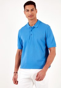 Polo azul en corte relajado, con mangas cortas, cuello y tres cierres de botones. Confeccionado en tejido texturizado.