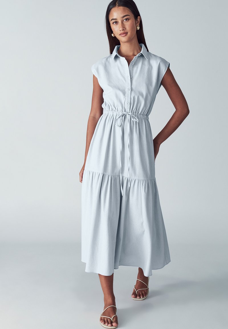 Abito midi azzurro chiaro con maniche corte, chiusura frontale a bottoni, vita elastica e gonna a strati. Tessuto morbido e dettaglio con stringa in vita.