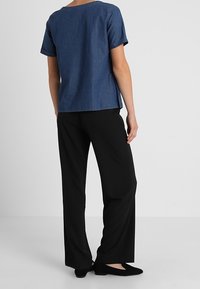 Top de manga corta en denim azul con escote redondo, combinado con pantalones de pierna ancha negros y bailarinas negras. Diseño sencillo, textura suave.