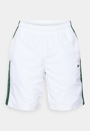 Shorts de sport blancs avec des accents verts sur les côtés, taille élastique, texture lisse, et un petit logo Lacoste sur le bas du côté.