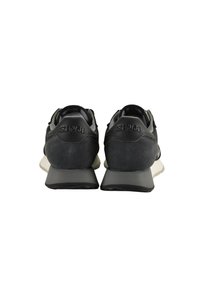 Scarpe sportive nere con una tomaia testurizzata, logo sul tallone e suola beige a contrasto. Forma arrotondata con colletto imbottito.