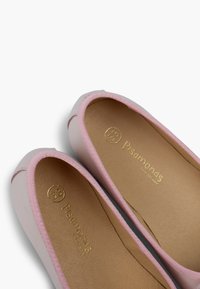 Ballerines rose clair avec un dessus en cuir lisse, des bordures en tissu rose et une semelle intérieure beige ornée d'une marque dorée.