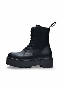 Botte en cuir noir à lacets avec une semelle épaisse et rainurée, bout rond et un subtil détail de couture blanche. Présente une sangle à l'arrière.