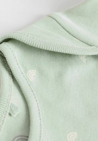 Mintgrön bomullstyg med en slät textur, som har små, subtila regnbågs mönster och en vikad krage design.