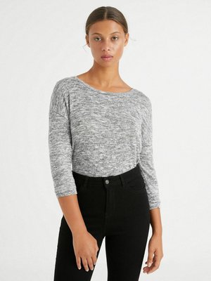 Top gris texturizado de manga larga con escote barco, combinado con jeans negros de tiro alto. Tejido suave, patrón sutil y diseño ajustado.