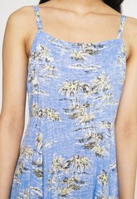 Niebieska sukienka bez rękawów z teksturowanej tkaniny, zdobiona nadrukiem palm w kolorze zielonym i czarnym oraz prostym dekoltem.