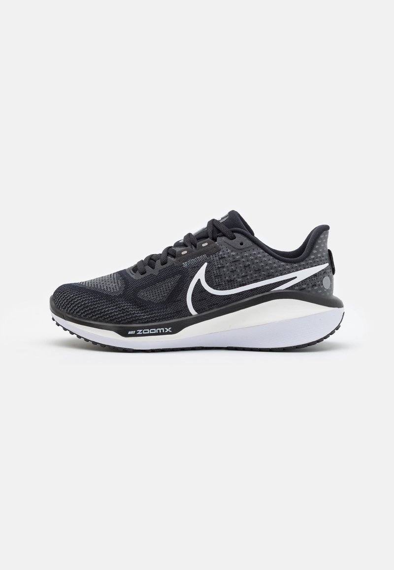Chaussure de sport noire avec un dessus texturé, un swoosh Nike blanc, une semelle rembourrée et un motif de semelle en caoutchouc distinct.
