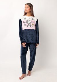 Conjunto de pijama de terciopelo en color navy, con una parte superior bloqueada en blanco y rosa que presenta un gráfico de Snoopy y copos de nieve, acompañado de pantalones a juego.