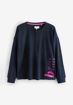 Navy long-sleeve top with a henley neckline, textured fabric, and a pink logo on the sleeve. Features buttons down the front and ribbed cuffs.