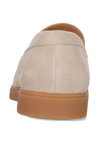 Beige mockask slip-on-sko med rund tå och en strukturerad tan gummisula, med sömmar längs sömmarna och minimal märkning.