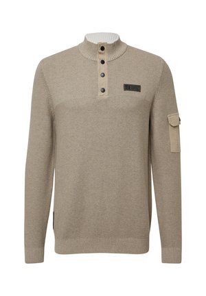 Bežani pleteni pulover s rebrastim visokim ovratnikom, četiri crna gumba, tkanim uzorkom na prsima i malim preklopnim džepom na lijevoj rukavi.