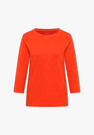 Jasnopomarańczowa koszula z długim rękawem, okrągłym dekoltem i prostym, niezdobionym wzorem, przedstawiona na jednolitym białym tle.