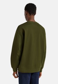 Sudadera verde aceituna con un corte relajado, cuello redondo, hombros caídos y puños de canalé. Fabricada con un suave tejido de mezcla de algodón.