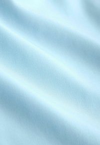 Tissu bleu clair doux avec de légers plis diagonaux et une texture lisse visible en gros plan.