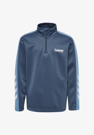 Dwoje dzieci noszących dopasowane niebieskie zestawy sportowe hummel z bluzami na zamek i wzorami w jodełkę na rękawach stoi na jednolitym tle.