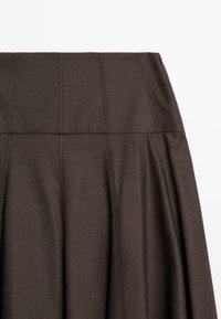Gonna plissettata marrone con vita alta, realizzata in tessuto texturizzato. Presenta cuciture verticali e una chiusura a zip nascosta.
