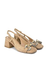 Tacchi slingback in suede beige con tacco a blocco, caratterizzati da una catena metallica decorativa e dettagli con pietre preziose nella zona delle punte.