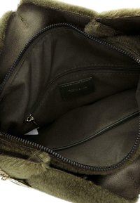 Olivegrüne Handtasche mit flauschiger Textur, das Innere umfasst eine Reißverschlusstasche und glattes Futter, ausgestattet mit einem Reißverschluss für sichere Aufbewahrung.