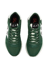 Las zapatillas de tela verde presentan un logo blanco en los laterales, cordones en contraste y un collar acolchado con un acento rojo en el interior.