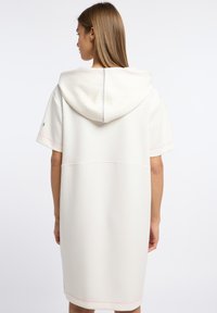 Witte hoodie jurk met korte mouwen, met een roze accentsteek en een eenvoudig, ontspannen ontwerp. Hete zachte textuur en een knielange snit.