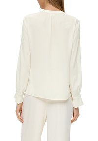 Weiße Bluse mit langen Ärmeln, Rundhalsausschnitt und geknöpften Manschetten. Weicher, glatter Stoff mit einer lockeren Passform und einem leicht abgerundeten Saum.