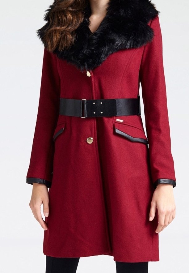 Manteau en laine rouge avec col en fausse fourrure noire, ceinture noire cintrée et bouton doré. Comprend des poches à rabat avec un bord noir.
