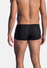 Pantaloni boxer neri realizzati in un materiale liscio e elastico. Presentano una vestibilità aderente con una cintura e un design minimalista, che mette in risalto una silhouette slanciata.