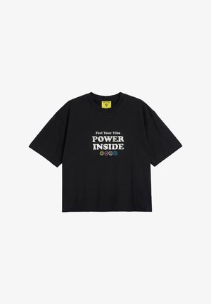 Czarna koszulka z krótkim rękawem z białym tekstem "Feel Your Vibe POWER INSIDE" i czterema małymi kolorowymi buźkami poniżej tekstu.