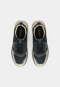 Σκούρες γκρι αθλητικές παπούτσια με άνω μέρος από διχτυωτό ύφασμα, καουτσούκ σόλα και αντίθετες μπεζ λεπτομέρειες. Διαθέτουν κορδόνια και λαβή στο τακούνι.