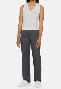 Top sans manches en tricot gris avec un col en V, associé à un pantalon droit gris foncé et des baskets blanches. Inclut un petit logo sur le haut.