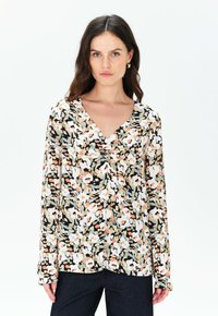 Blusa a fantasia floreale con scollatura a V, maniche lunghe, nei colori nero, bianco, beige e tonalità pastello. Tessuto leggero con una consistenza morbida.