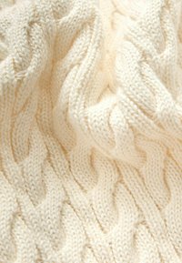 Cremefarbener gestrickter Stoff mit einem strukturierten Kabelmuster und erhabenen, ineinander verschlungenen Designs. Weiche und dicke Textur mit einem gemütlichen Aussehen.