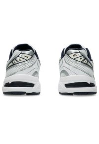 Verkkokangasta olevat juoksukengät, joissa on valkoinen ja hopea päällinen, laivaston sinisiä yksityiskohtia ja GEL-vaimennusteknologiaa; teksturoitu takapaneeli ja kumipohja.