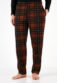 Pantalones de pijama a cuadros marrones y negros, hechos de una tela suave, con una cinturilla elástica y bolsillos laterales, de corte relajado.