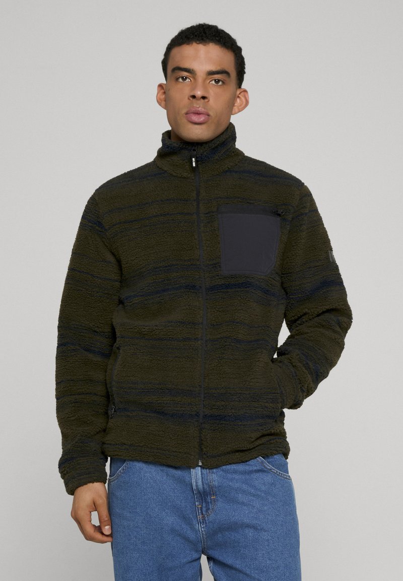 Fleecejakke i mørkegrønn med svarte striper, høy krage, hel frontglidelås og en brystlomme i ensfarget svart stoff.