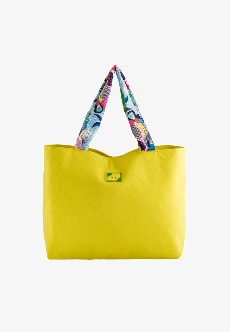 Yellow tote bag with a textured finish and a colorful patterned fabric handle featuring multicolored graphics. Includes a small label.