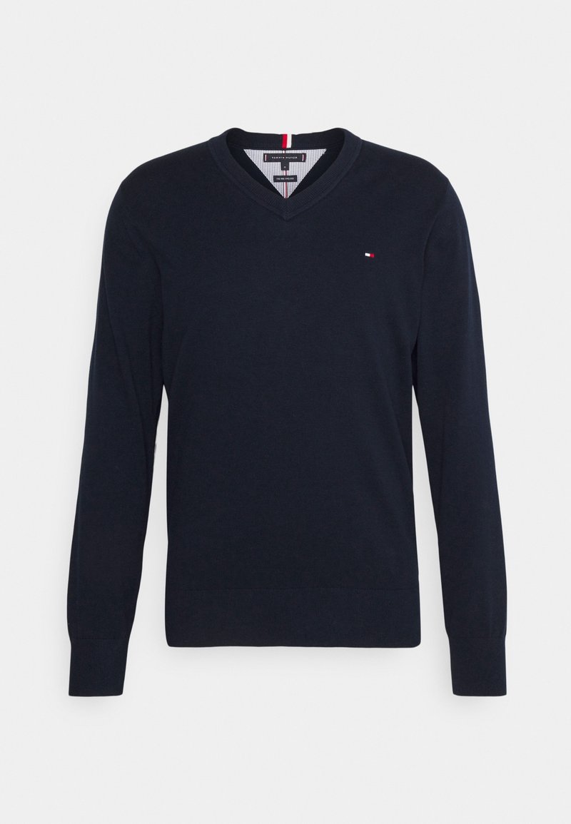 Pull à manches longues en laine bleu marine avec col en V, logo rouge, blanc et bleu sur la poitrine gauche, poignets et ourlet côtelés.