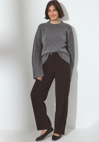Gray knit sweater with a ribbed hem, paired with high-waisted black wide-leg pants. Black flat shoes complete the outfit.