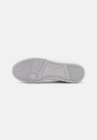 White rubber sole with patterned tread and Lacoste branding. Features a smooth texture and rounded design for footwear support.
