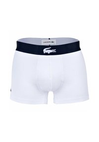 Boxer shorts en coton blanc avec une ceinture élastique marine arborant un logo Lacoste. Texture lisse, coupe ajustée et design à jambe courte.