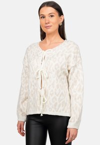 Pullover in maglia con stampa leopardata bianca, scollo a V, lacci centrali, polsini e orlo a costine. Tessuto morbido con una vestibilità svasata.
