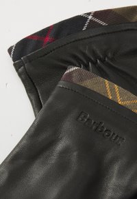 Luvas de pele pretas com um forro interno em padrão xadrez nas tonalidades de castanho, vermelho e amarelo, e o nome da marca "Barbour" gravado no exterior.