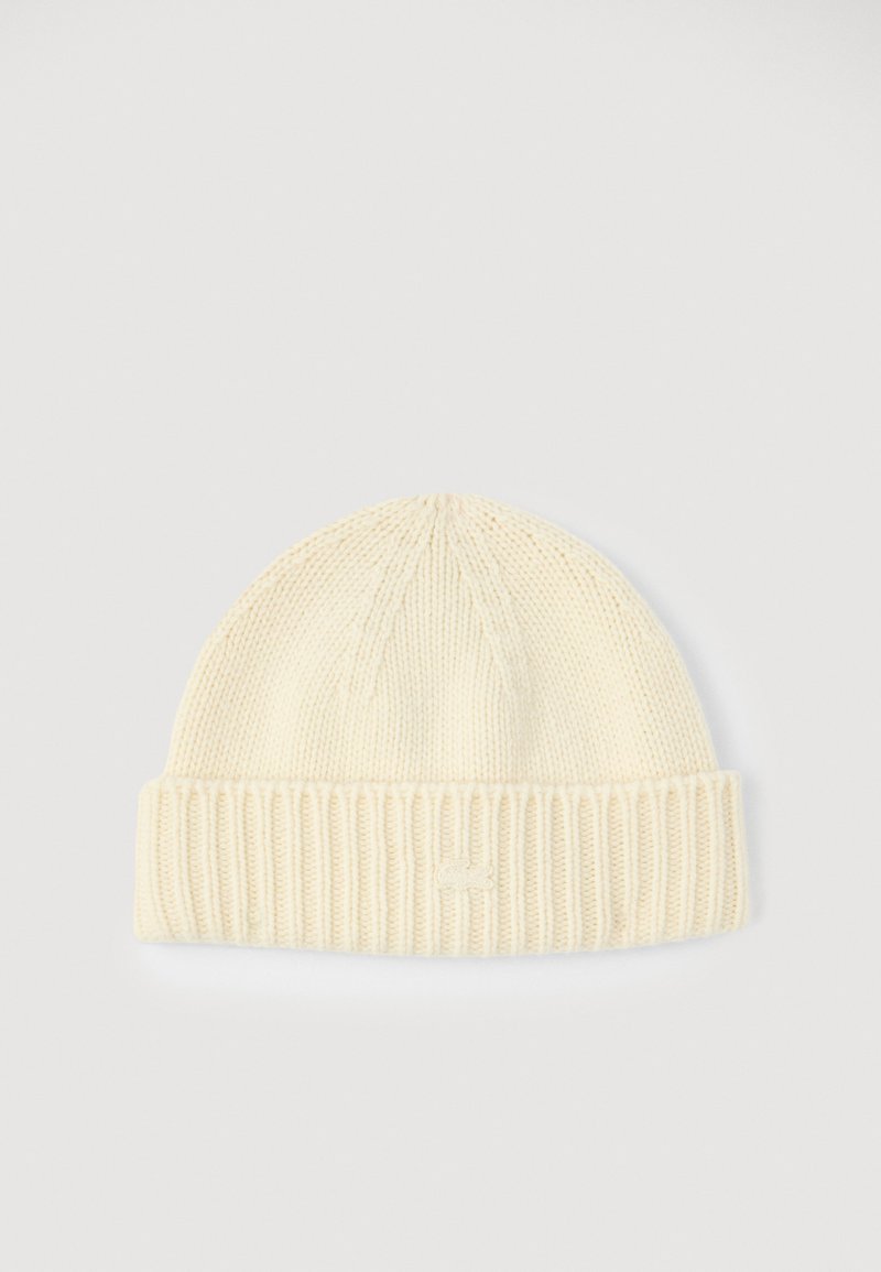 Căciulă tricotată de culoare crem, cu un model în crești și cu o manșetă pliată. Fabricată dintr-un material moale și texturat, cu un detaliu mic cu logo în față.