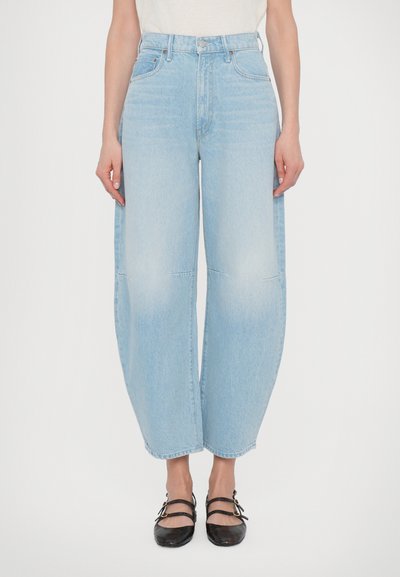 Lysblå denim bredbente jeans med høj talje, der har lommer og en ren kant. Bæres med sorte, snørede balletflader.