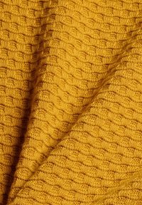 Tissu tricoté jaune moutarde avec un motif en nid d'abeille texturé et des plis doux.