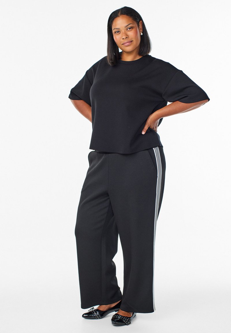 Black short-sleeve top and black wide-leg pants with white side stripes, paired with black embellished shoes. Smooth fabric, relaxed fit.