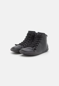 Scarpe nere alte in pelle con punte arrotondate, dotate di un sistema di allacciatura frontale e suole in gomma piatta. Dettagli di cucitura in accentuazione.